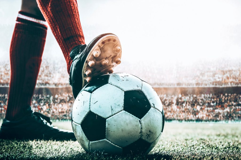 feet of soccer player tread on soccer ball for kick off in the stadium
